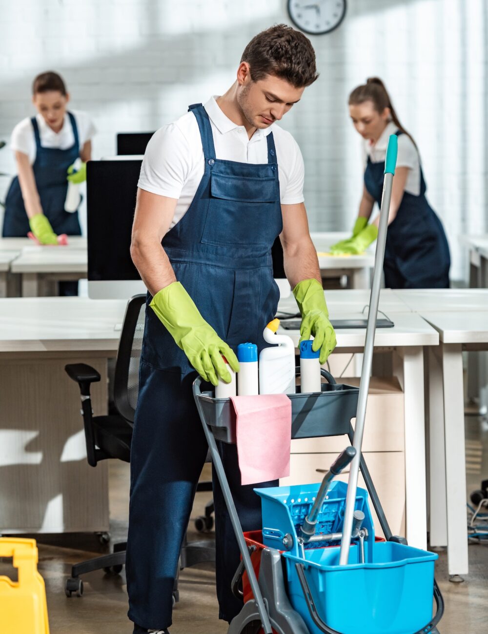 young-cleaner-standing-near-cart-with-cleaning-supplies.jpg